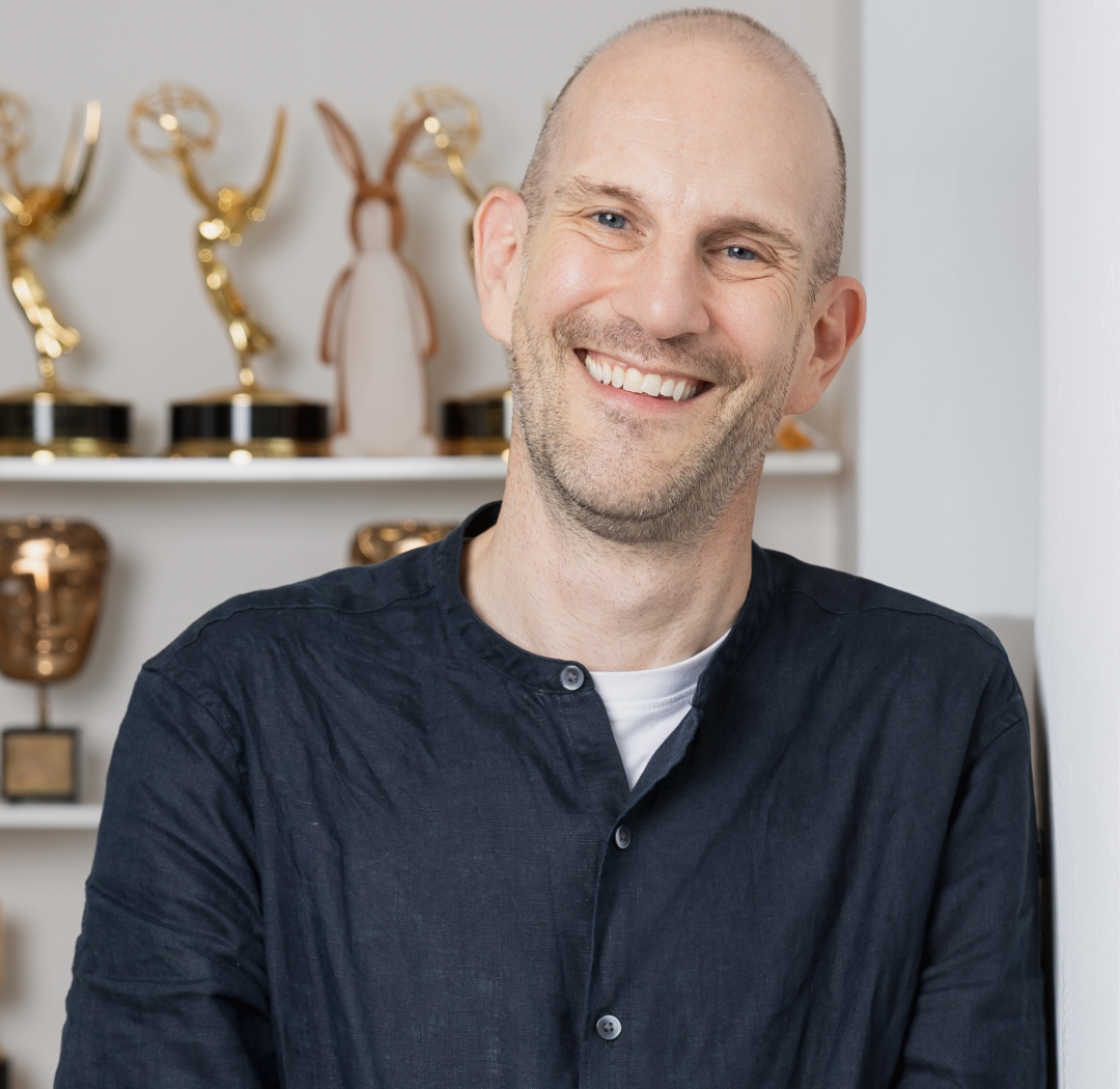 Marc Ollington smiles with awards in the background