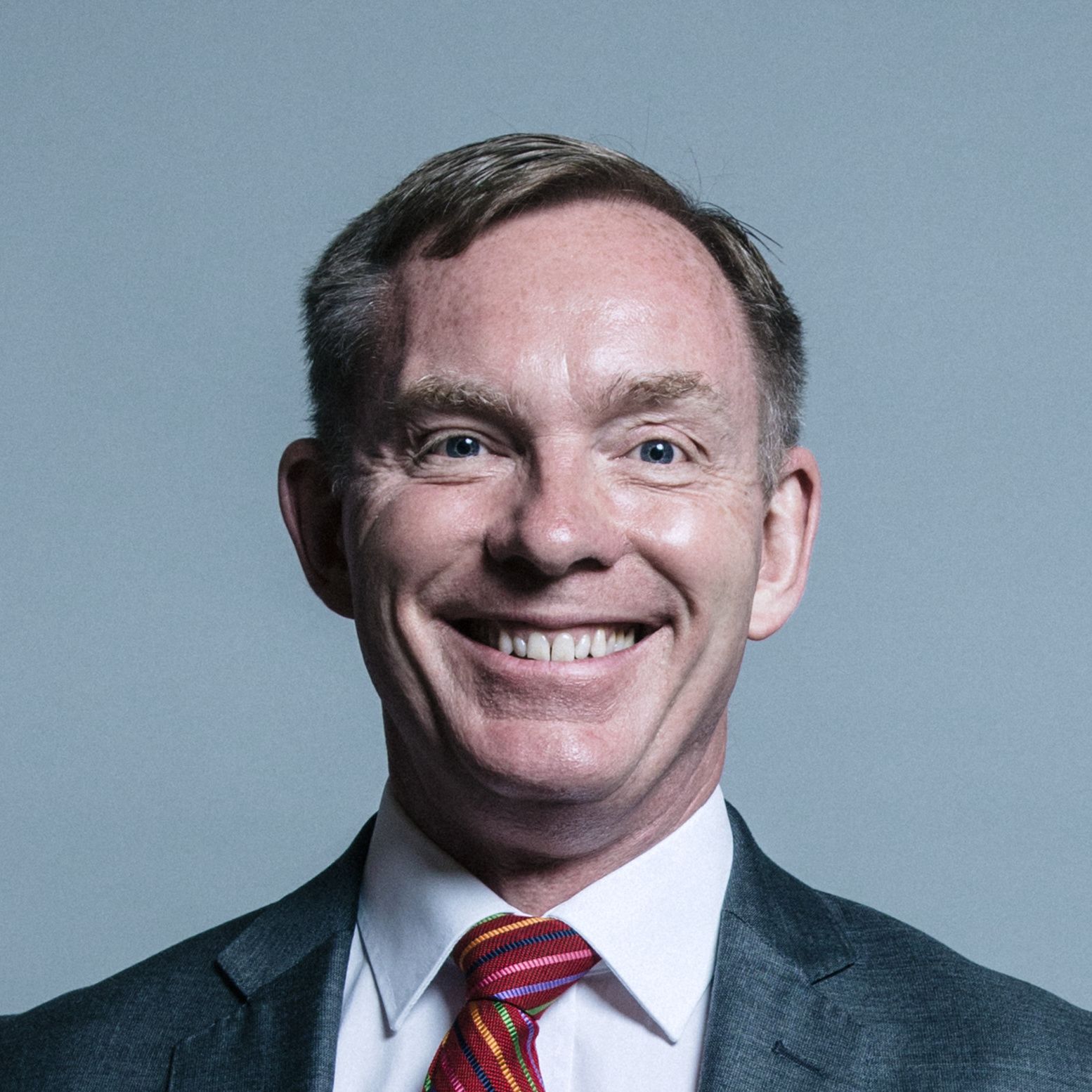 Sir Chris Bryant, smiling wearing a suit and colourful tie