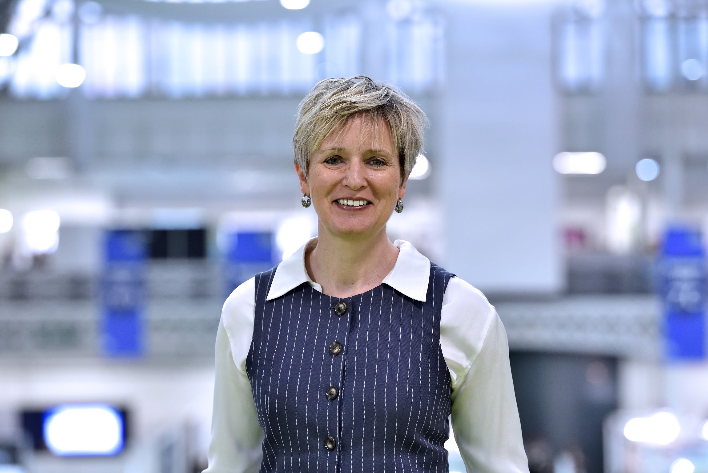 Mandy Hill, wearing a white top and blue waistcoat smiles at the camera