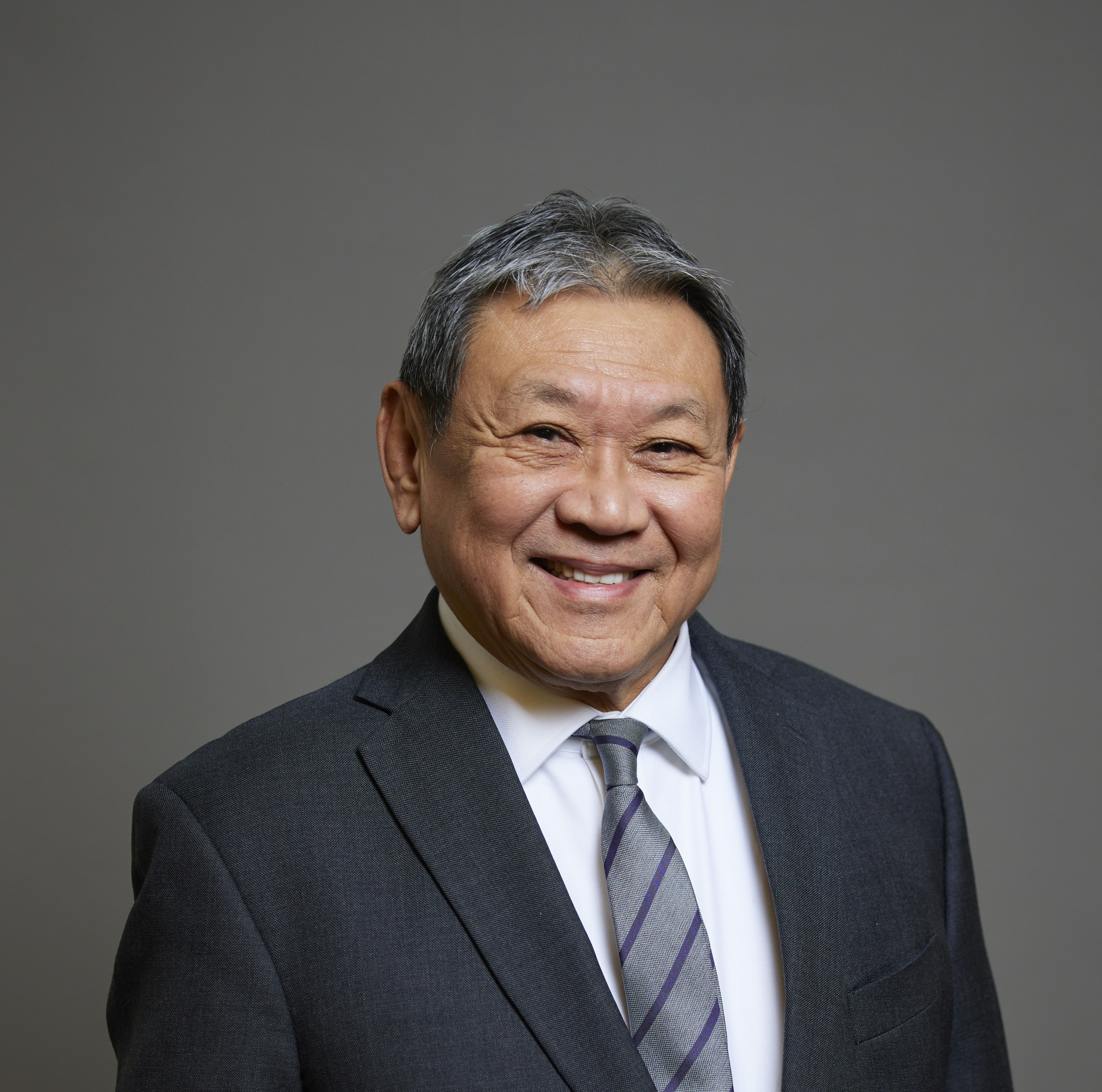 Lord Leong smiles at the camera wearing a suit and striped tie